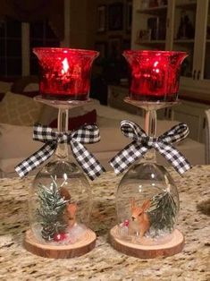 two wine glasses with christmas decorations on them sitting on a counter top next to each other