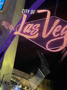 the city of las vegas sign is lit up in purple and yellow lights at night