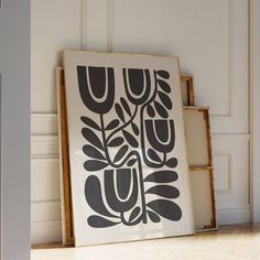 a black and white art piece sitting on top of a wooden floor next to a wall