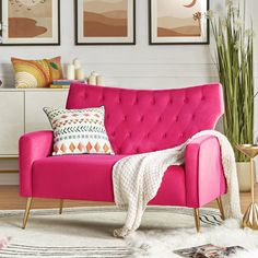 a living room with pink couches and pictures on the wall above it, along with rugs