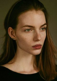 a woman with long brown hair and green eyes looks at the camera while wearing a black shirt