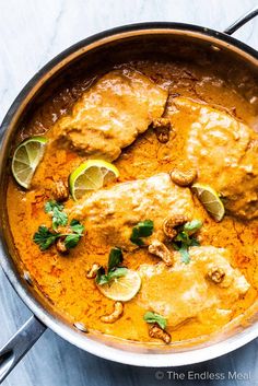 chicken curry in a pan with limes and cilantro