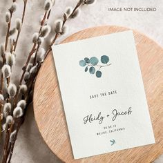 the save the date card is on top of a wooden plate next to some flowers