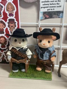 two stuffed animals are posed next to each other in front of a wall with pictures on it