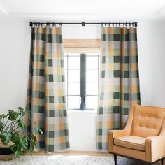 a chair sitting in front of a window next to a green and yellow checkered curtain