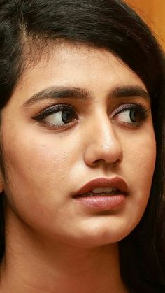 a close up of a woman with dark hair and eyeliners looking at the camera