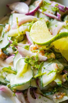 a salad with cucumbers, onions and lemon wedges