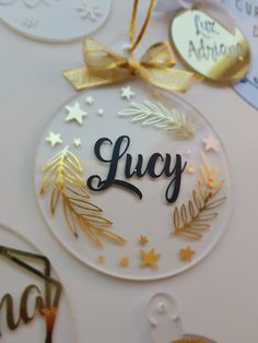 a glass ornament with the word lucy on it and gold stars around it