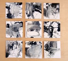 six black and white paintings are arranged on a wooden surface, each with different shapes