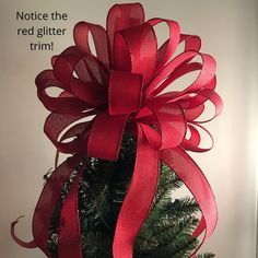 a christmas tree with a red ribbon on it's top and the words notice the red glitter trim