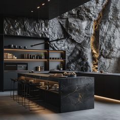 a large kitchen with black cabinets and counter tops in front of a rock - like wall