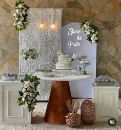 a table topped with a cake next to two vases filled with flowers and greenery