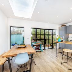 an open kitchen and dining area with wood flooring, stainless steel appliances and skylights