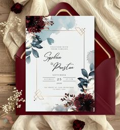 an elegant wedding card with flowers and leaves on the front is displayed in red paper