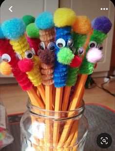 a glass jar filled with lots of colorful pom - poms on top of a table