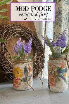 two vases with flowers in them sitting on a window sill next to a wreath