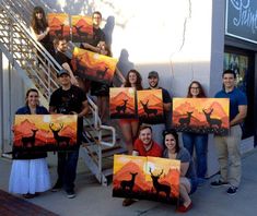 a group of people holding up paintings in front of a building