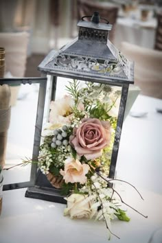 a lantern with flowers and greenery on it