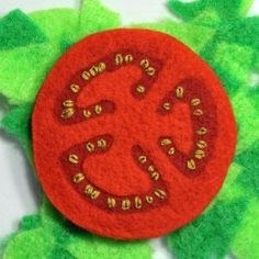 a red button sitting on top of green leafy material with words written in gold