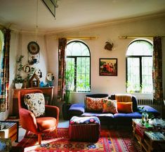 a living room filled with lots of furniture next to two large windows and a colorful rug on the floor