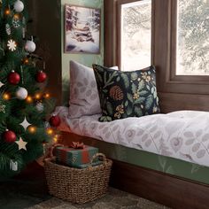 a christmas tree is in the corner of a room with a bed and window sill