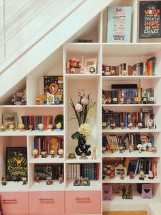 a bookshelf filled with lots of books next to a stair case in a room