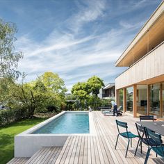 a wooden deck next to a swimming pool with chairs and tables on top of it