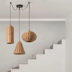 three wicker lamps hanging from the ceiling in a room with white walls and stairs