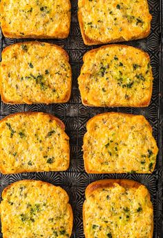 several square pieces of bread with cheese and herbs on them sitting on a cooling rack