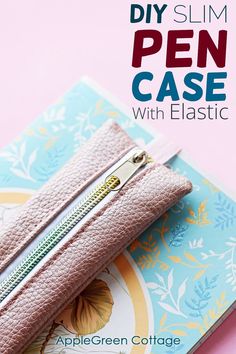 a pink zipper case sitting on top of a notebook with the words diy slim pen case