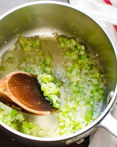 a pot filled with green vegetables and a wooden spoon