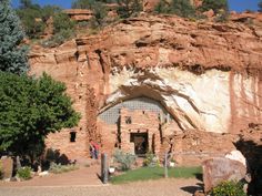 an entrance to a cave in the side of a mountain with trees and bushes around it