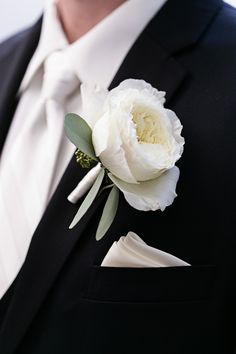 a man in a tuxedo with a white flower on his lapel pin