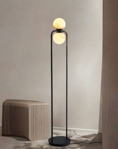 the floor lamp has two balls on it and is next to a block of concrete