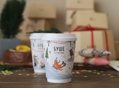 two coffee cups sitting on top of a wooden table next to boxes and other items