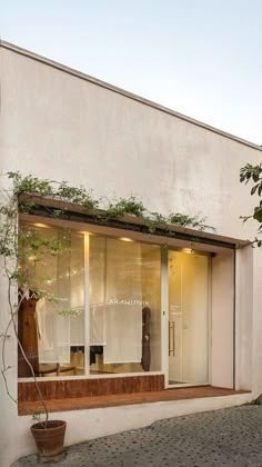 a store front with plants growing out of the window and on the outside wall, next to a potted tree