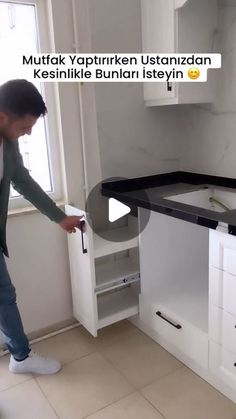 a man standing in front of a kitchen counter top with an open drawer on it