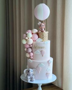 a three tiered cake decorated with balloons and animals