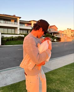 a man holding a baby in his arms on the side of a road next to a building