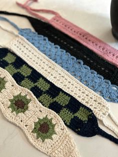 four crocheted ribbons are lined up on a table