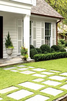 a white house with green grass in the yard and potted plants on the front lawn