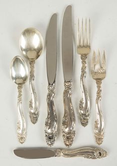 an assortment of silverware including forks, knives and spoons on a white surface