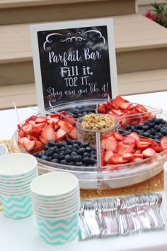 a table topped with plates and cups filled with fruit next to a sign that says parfait bar full it top it