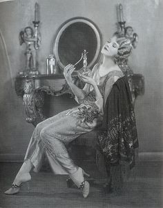 an old fashion photo of a woman sitting in front of a mirror