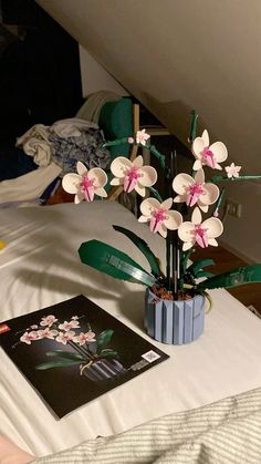 there is a vase with flowers in it on the bed next to a book and magazine