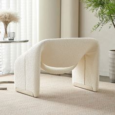 a white chair sitting on top of a rug next to a table with a potted plant