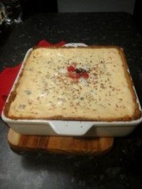 a square casserole dish sitting on top of a wooden cutting board