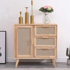 a wooden cabinet with three drawers and two vases on top