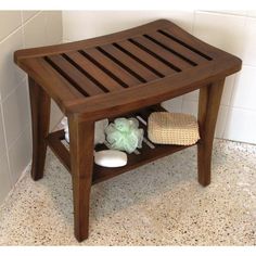 a small wooden bench in the corner of a room with white tile on the floor