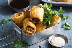 some food is in a metal container on a table next to a spoon and sauce